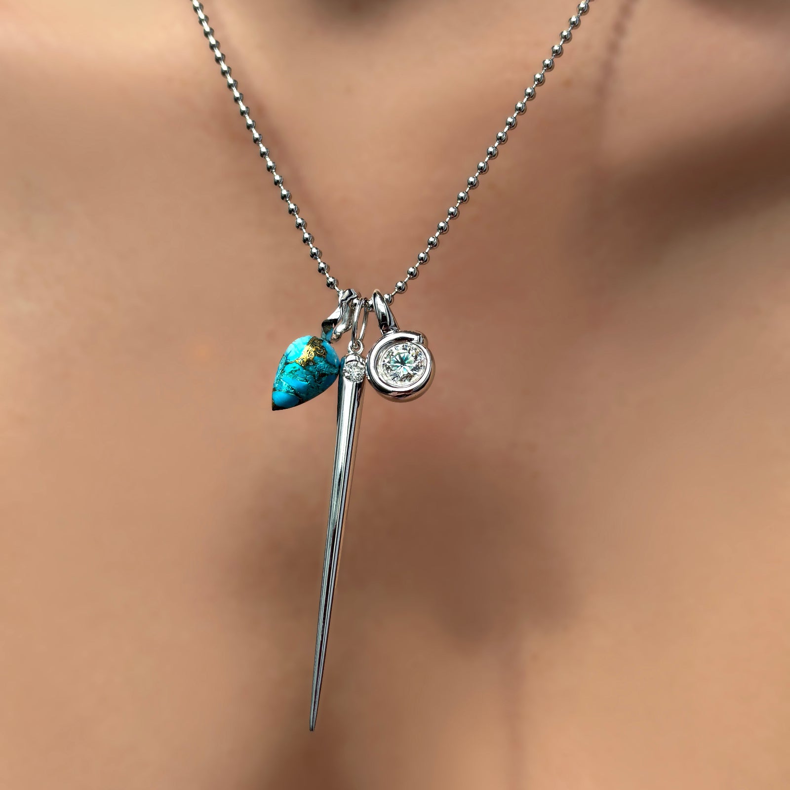2mm bead chain with turquoise drop charm, quill spike charm with diamond, and quill bezel charm with diamond on a model's neck.