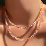 Two blush sapphire necklaces layered on a model's neck.