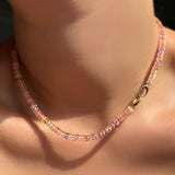 Multi blush padparadscha sapphire necklace on a model's neck with the 14k yellow gold clasp turned towards the front.