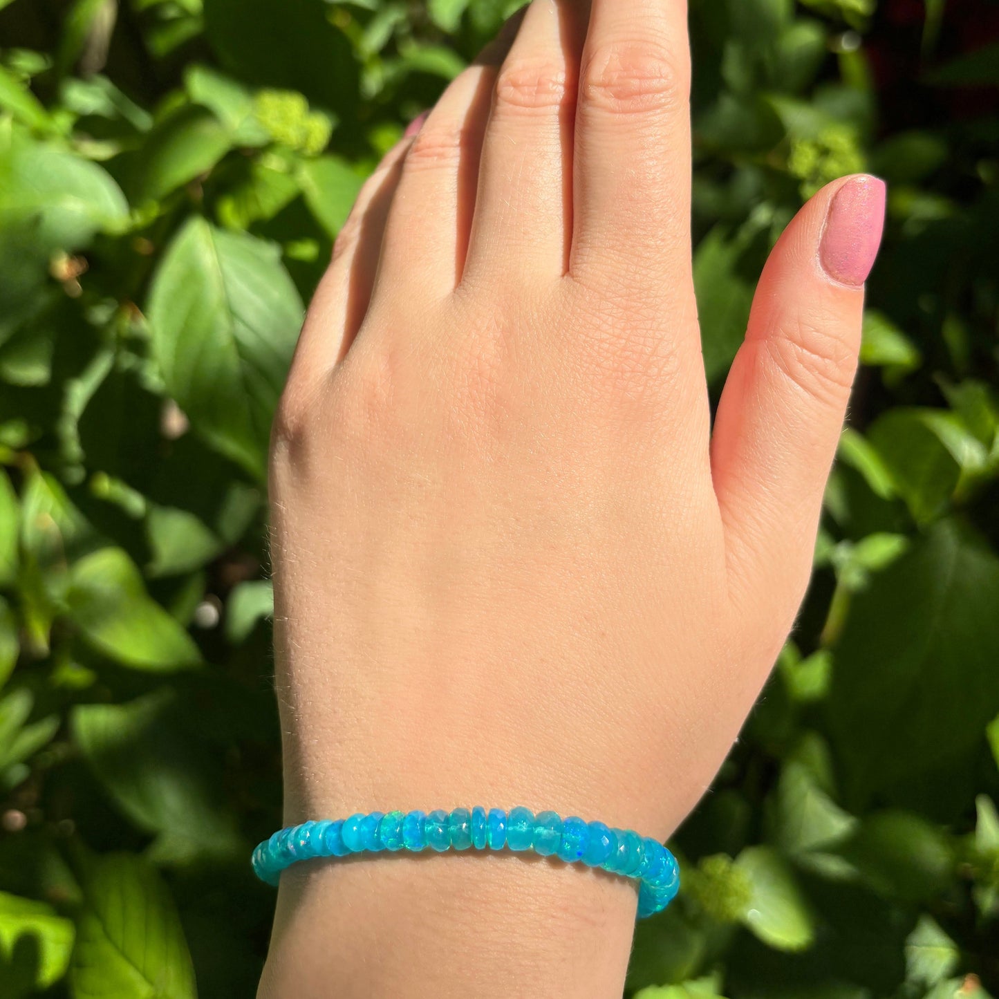 Shimmering beaded bracelet made of faceted opals in shades of bright blue on a gold linking lobster clasp. 