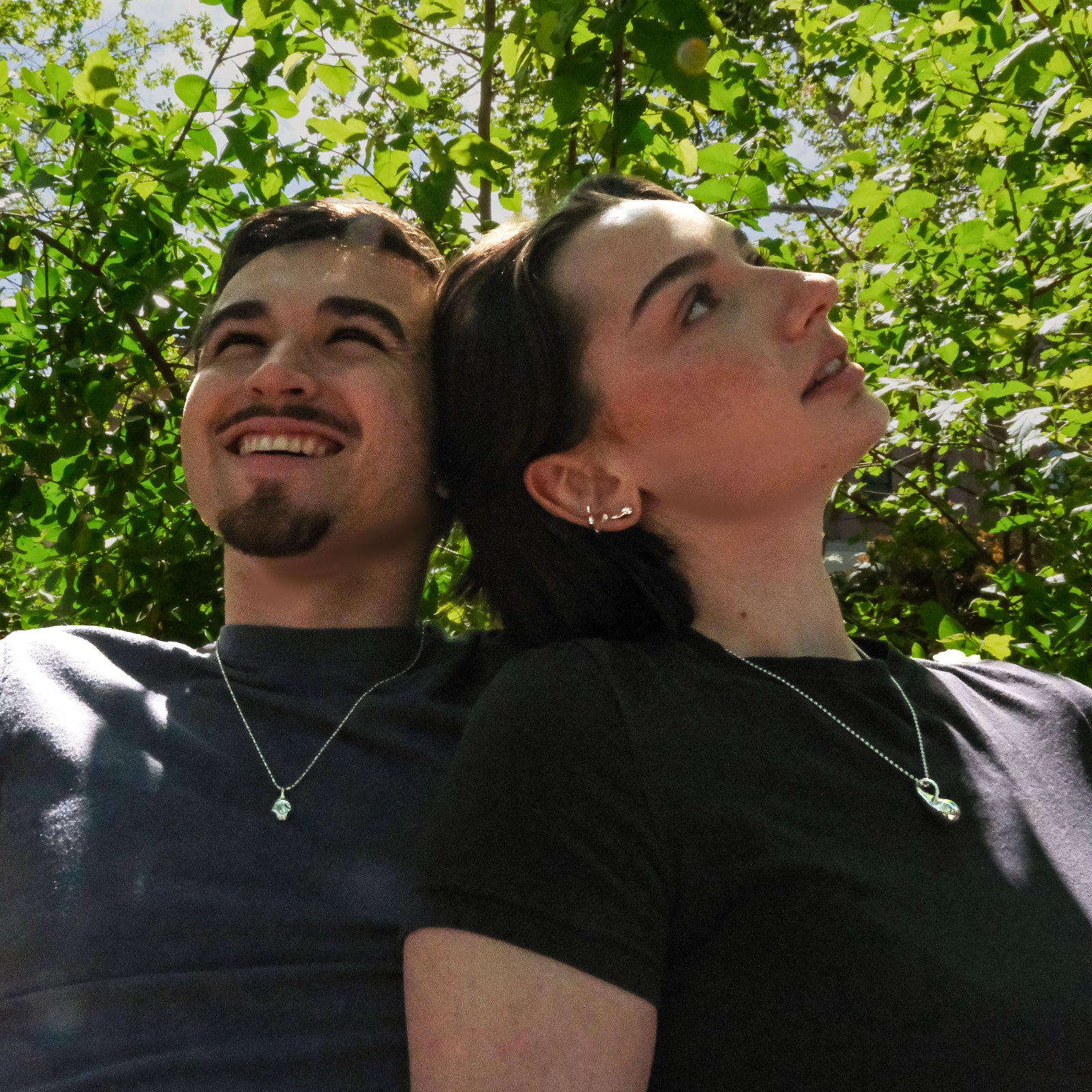 Two people sitting together with trees in the background, both wearing AMANDA PEARL molten sterling silver jewelry.