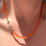 AMANDA PEARL faceted carnelian necklace with paperclip charm lock with lapis on a model's neck.