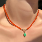 Faceted carnelian with a chrysoprase drop charm hanging in the linking ovals clasp on a model's neck.