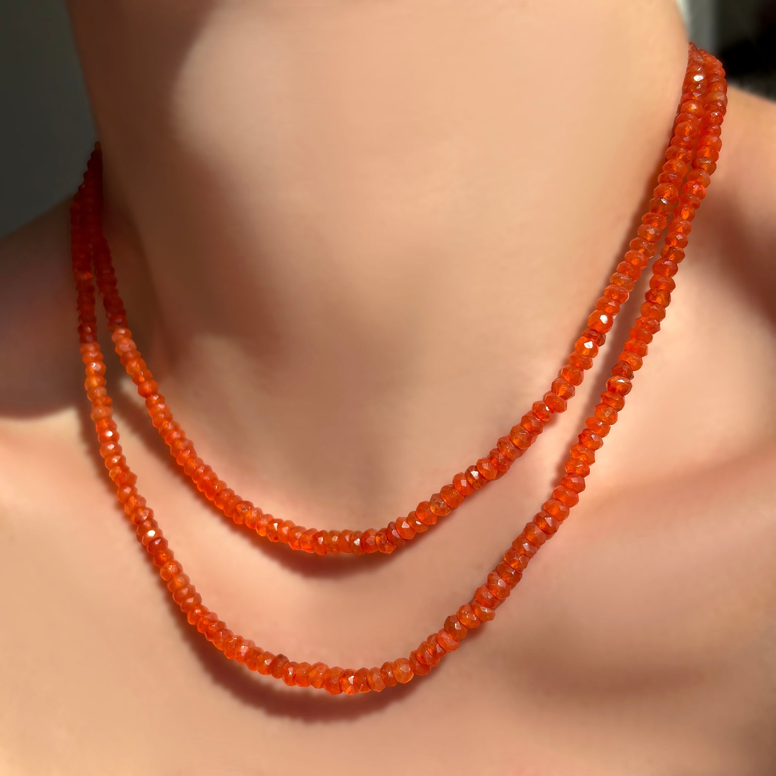 2 faceted carnelian gemstone necklaces layered on a model's neck.