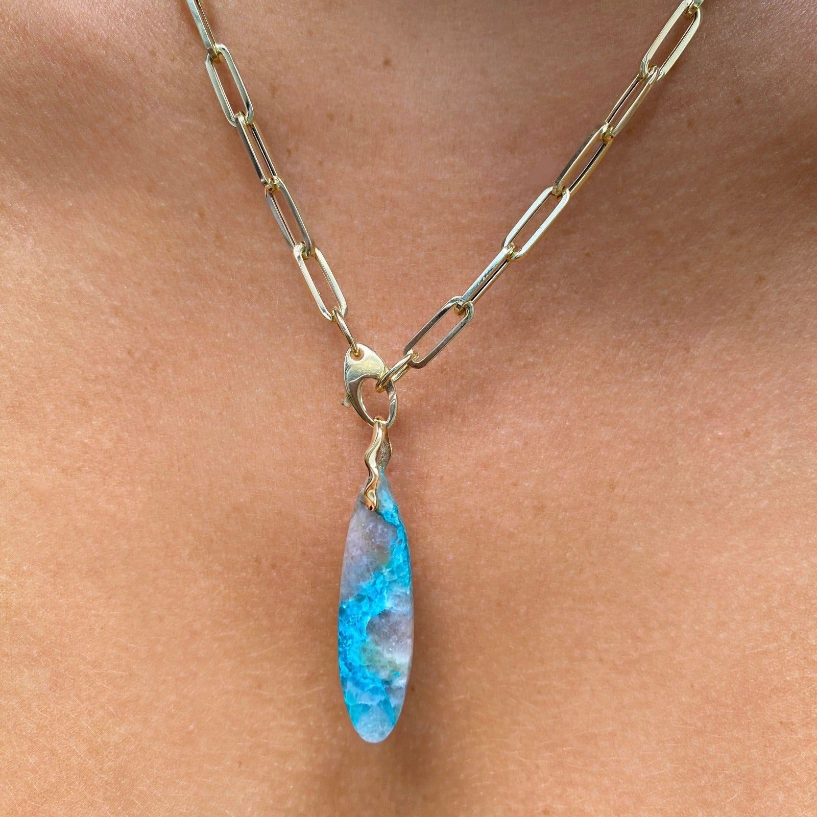 Chrysocolla in Quartz Surfboard Charm. Styled on a neck hanging from the lobster clasp of a paperclip chain necklace.