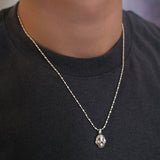 AMANDA PAERL recycled sterling silver cylinder chain necklace with a molten skull charm on a person wearing a black shirt.