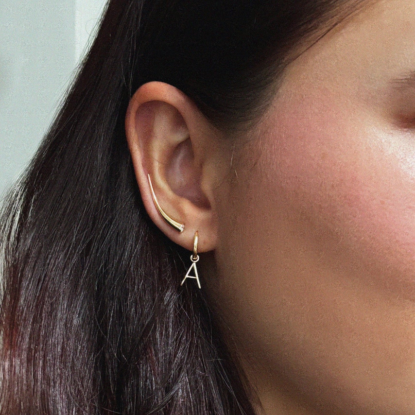 14k gold Letter "A" Huggie styled on an ear with our Quill Climber in the second hole.