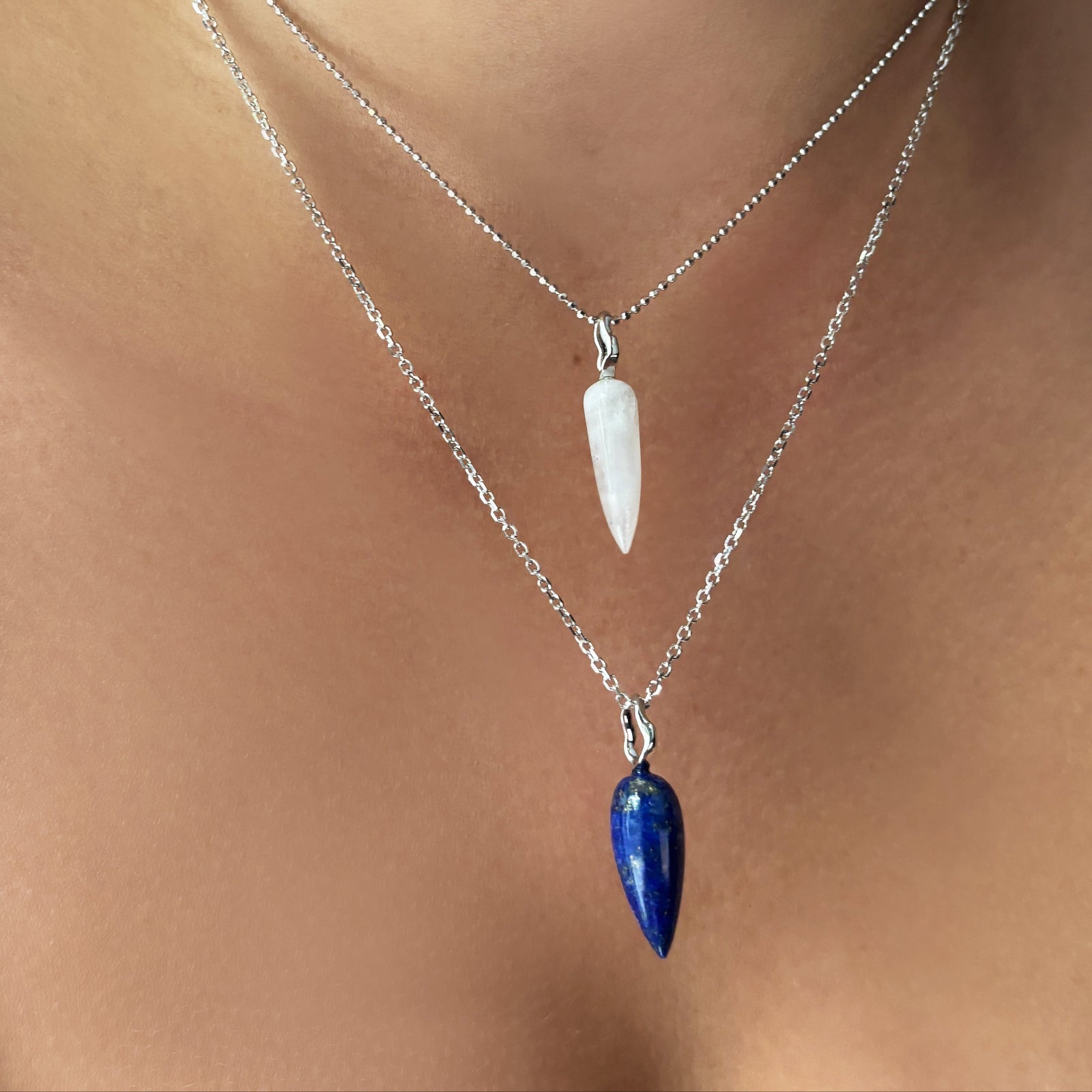 diamond cut cable chain and bead chain with moonstone drop charm and lapis drop charm on the neck.