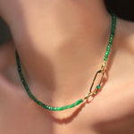 Faceted Emerald Necklace with Paperclip Charm lock with green onyx cabochon on a model's neck.