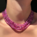 Stack of fuchsia faceted sapphire necklaces on a model's neck.