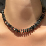 faceted rutilated quartz necklace with neon red thread on a model's neck in the sun.