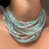 A stack of AMANDA PEARL faceted aquamarine beaded necklaces on a model's neck.