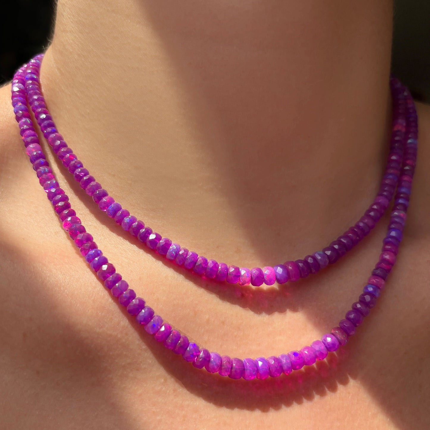 Shimmering beaded necklace made of faceted opals in shades of fuchsia pink on a gold linking ovals clasp. 