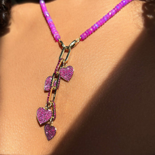 Ruby heart charms on ruby charm locks on a fuchsia faceted opal necklace layered together. 