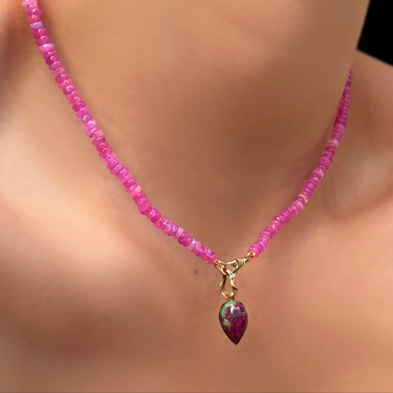fuchsia opal necklace with ruby zoisite drop charm hanging on a model's neck.