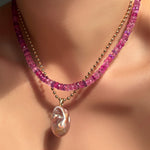 Fuchsia faceted sapphire necklace layered over a 3mm bead chain with blush baroque pearl on a model's neck.
