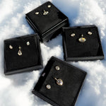Gift boxes of molten solitaire charms and studs in the snow for the holidays.