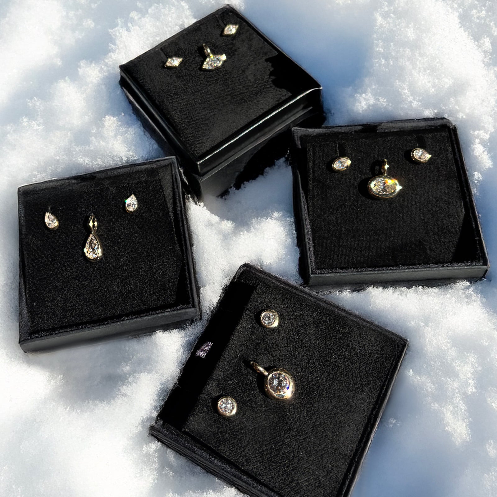 Gift boxes of molten solitaire charms and studs in the snow for the holidays.