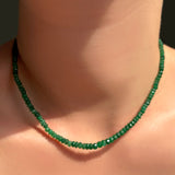 single green faceted emerald necklace on a model's neck.