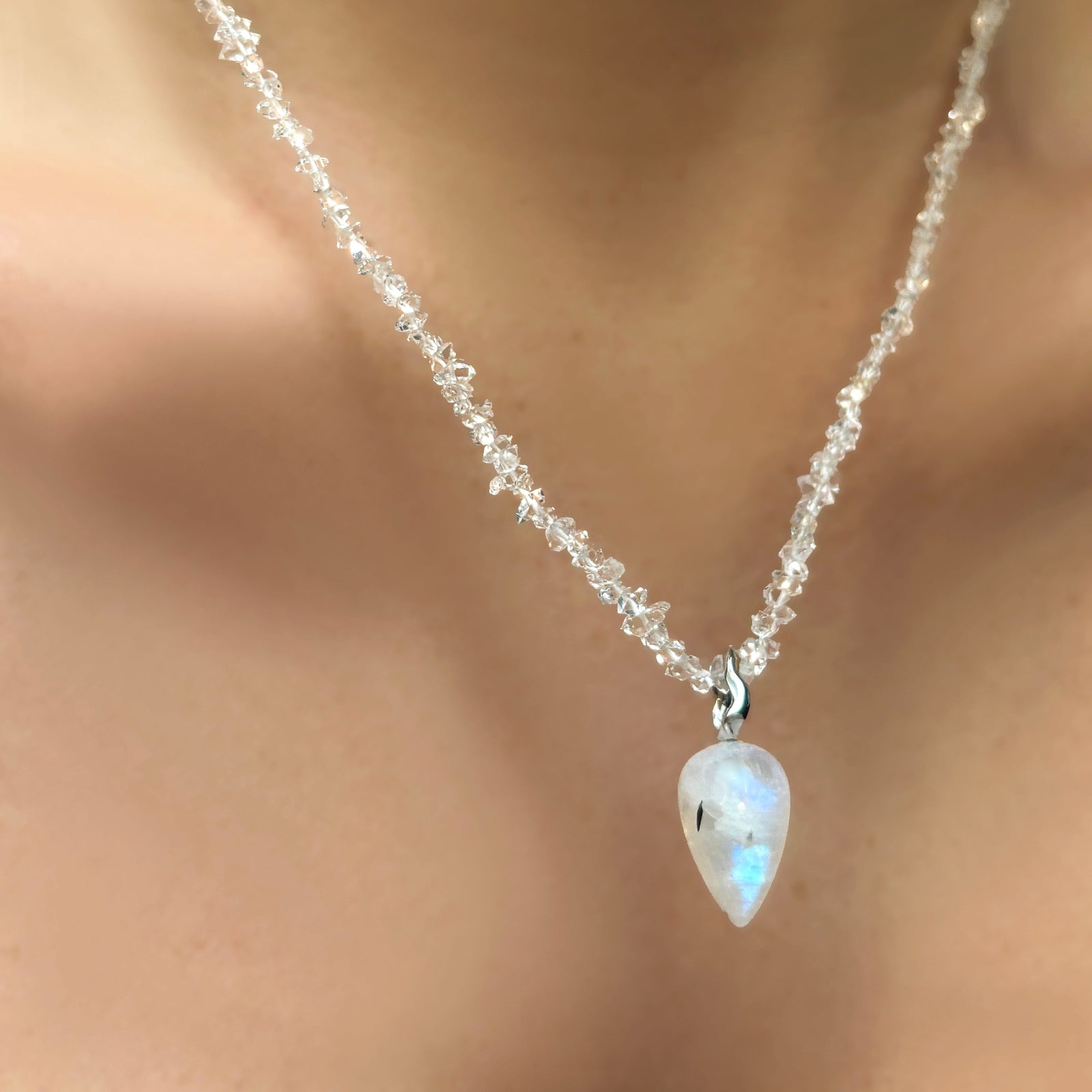 Herkimer Diamond necklace with large Rainbow Moonstone drop charm with white gold ripple bale hanging from a model's neck.