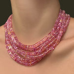 Multiple hibiscus sapphire necklaces layered on a model's neck.