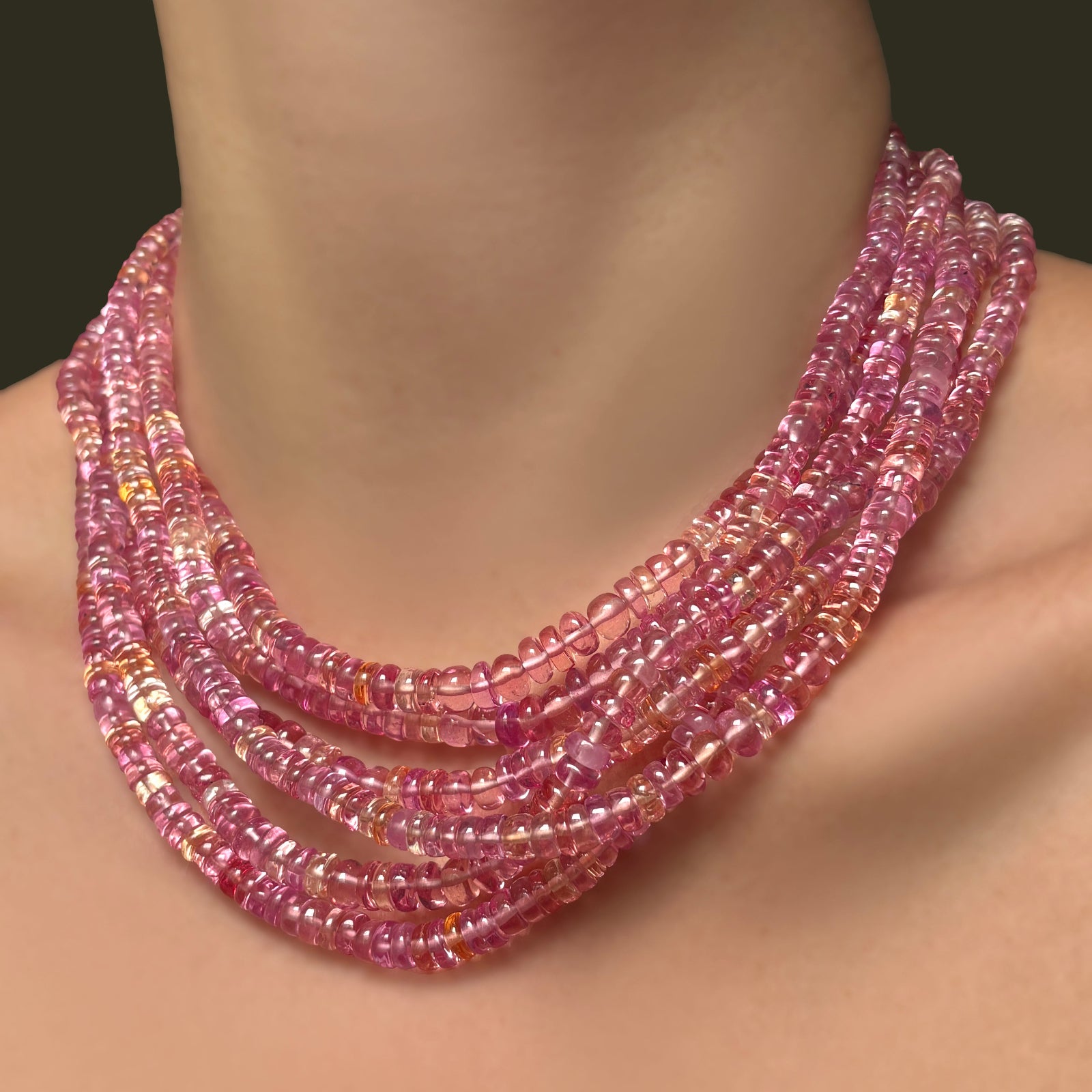 Multiple hibiscus sapphire necklaces layered on a model's neck.