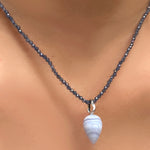 A close-up of lace agate charm drop with a recycled white gold 14K bale hangs on a deep grey purple iolite necklace with faceted sparkling beads.