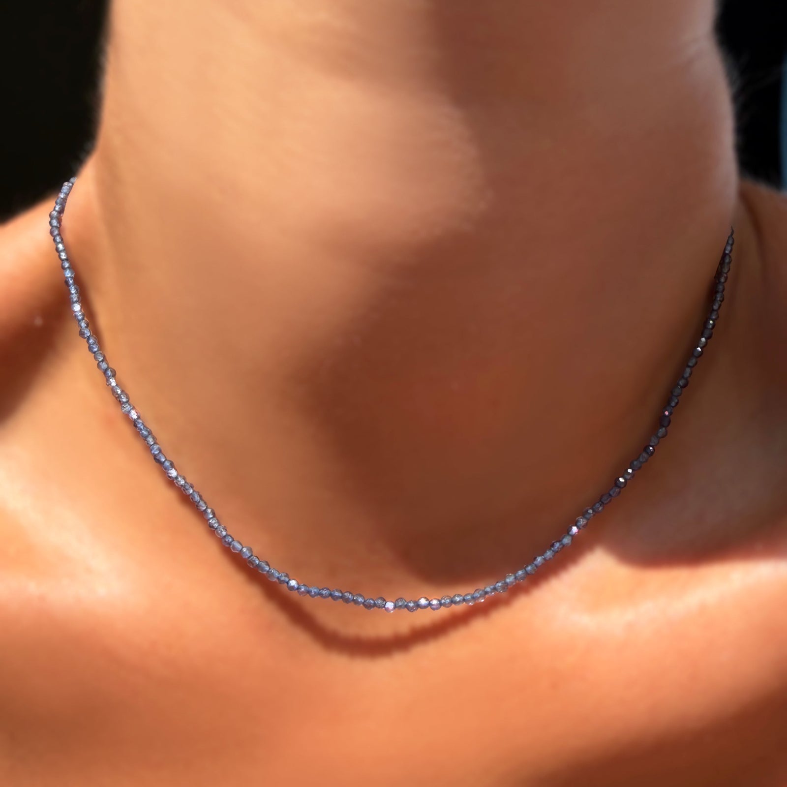 An AMANDA PEARL 2mm faceted iolite beaded necklace on a model's neck.