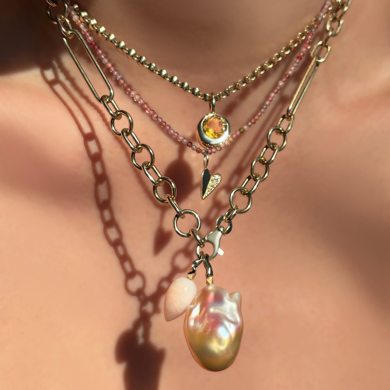 Close-up of a necklace with a pearl pendant on a model's neck.