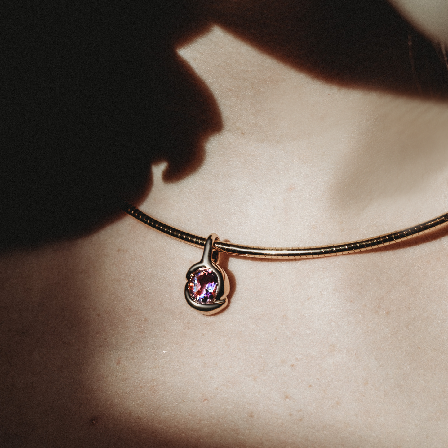 Molten knot charm with gemstone. Styled on a neck hanging from the omega chocker necklace.