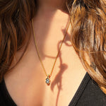 AMANDA PEARL Molten knot charm in recycled 14k yellow gold with an ethical diamond, on a 2mm bead chain on a model's neck.