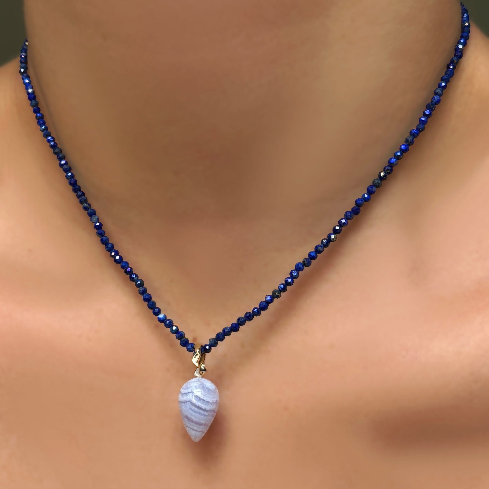 Lapis slim gemstone necklace with blue lace agate drop charm with ripple bale, layered on a model's neck.