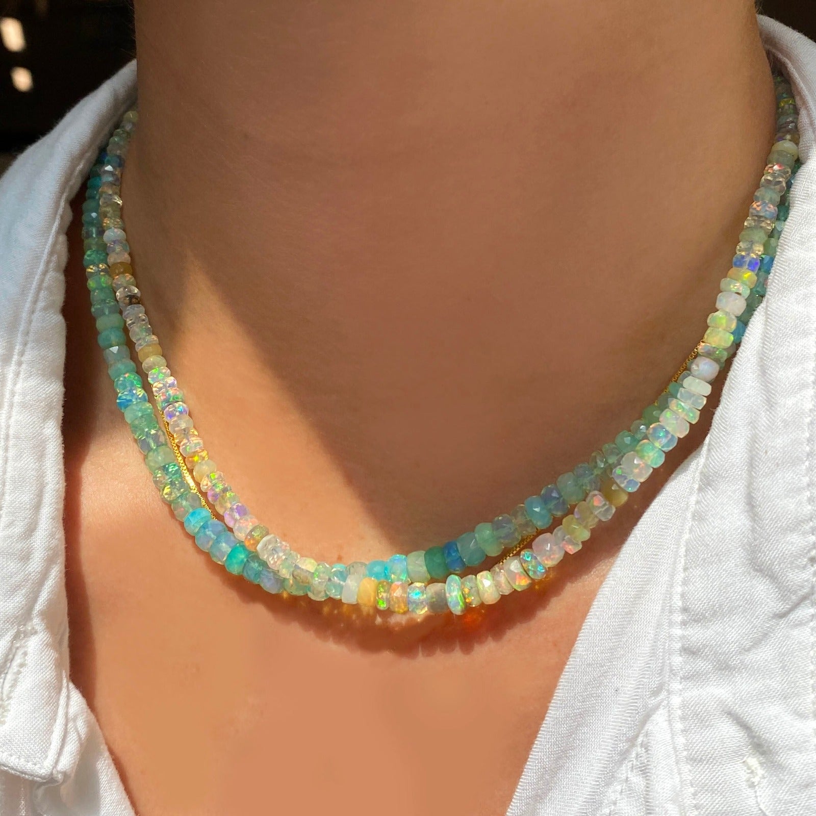 Shimmering beaded necklace made of faceted opals in shades of white, clear, and yellow on a gold linking ovals clasp. 