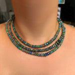 Low light faceted opal necklaces layered on the neck in the light.