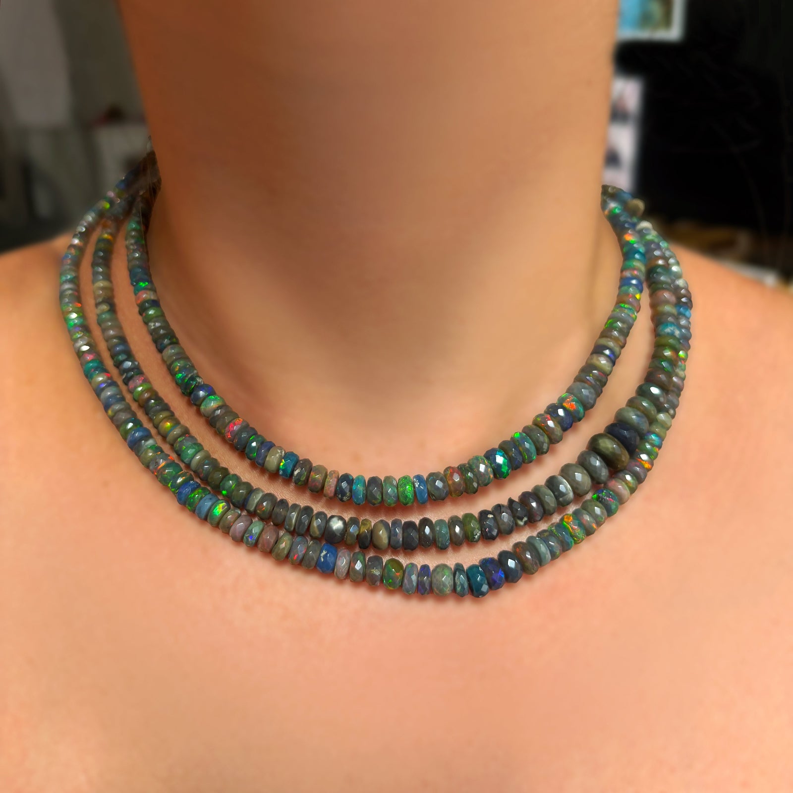 Low light faceted opal necklaces layered on the neck in the light.