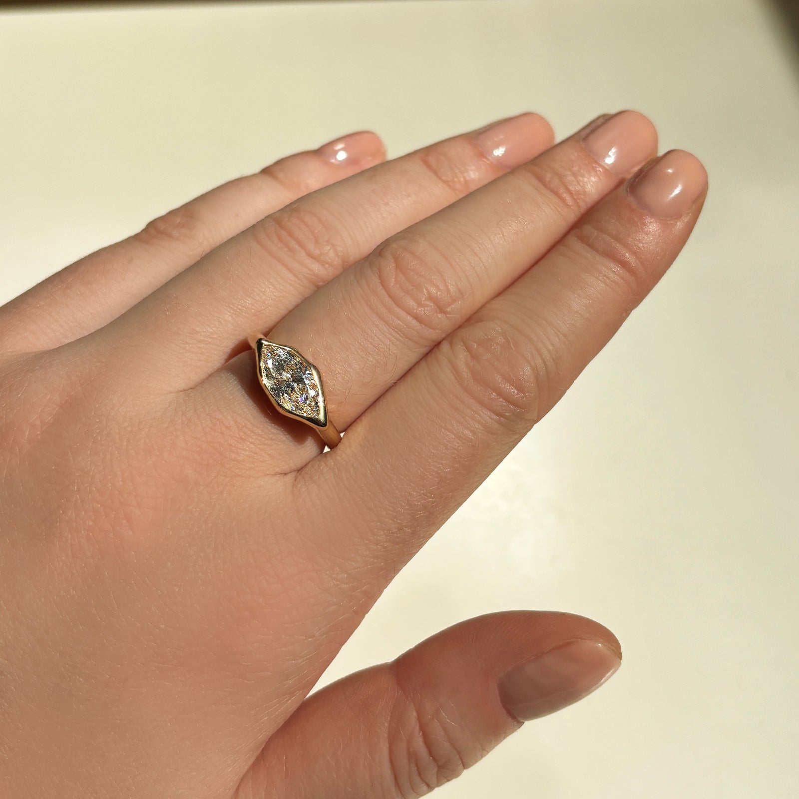 marquise molten solitaire ring  on a middle finger