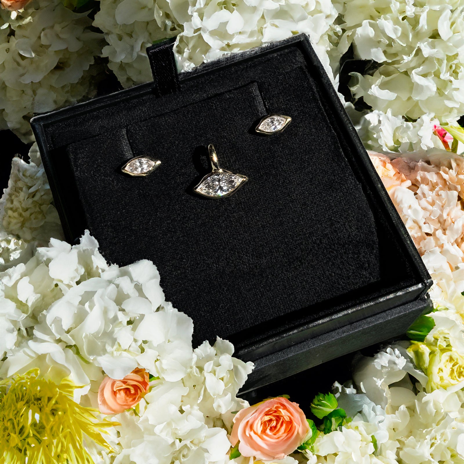 Gift box with marquise solitaire studs and charm with flowers.
