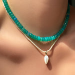 Blue faceted opal necklace layered on the neck over a pearl slim gemstone necklace and mother of pearl drop charm.