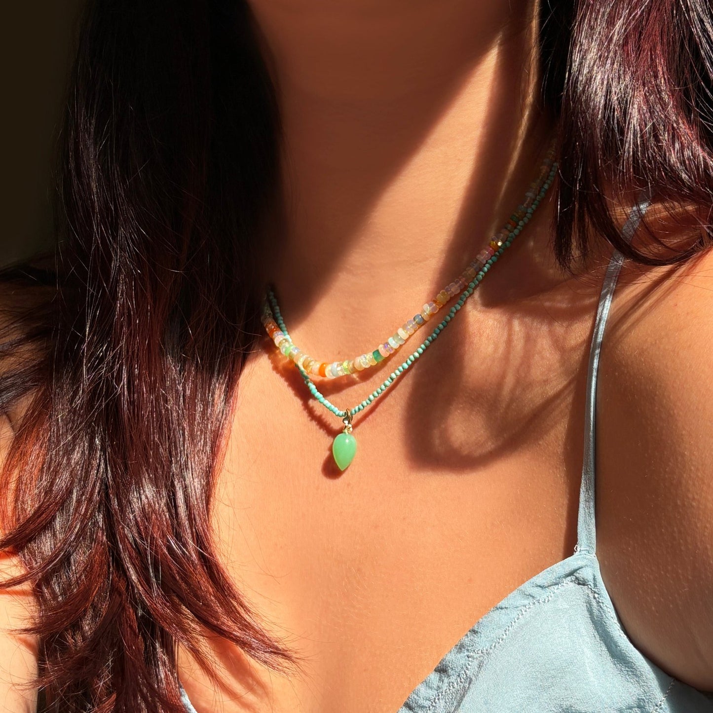 Chrysoprase acorn drop charm with green tones with 14k gold ripple bale on a turquoise slim gemstone on a neck