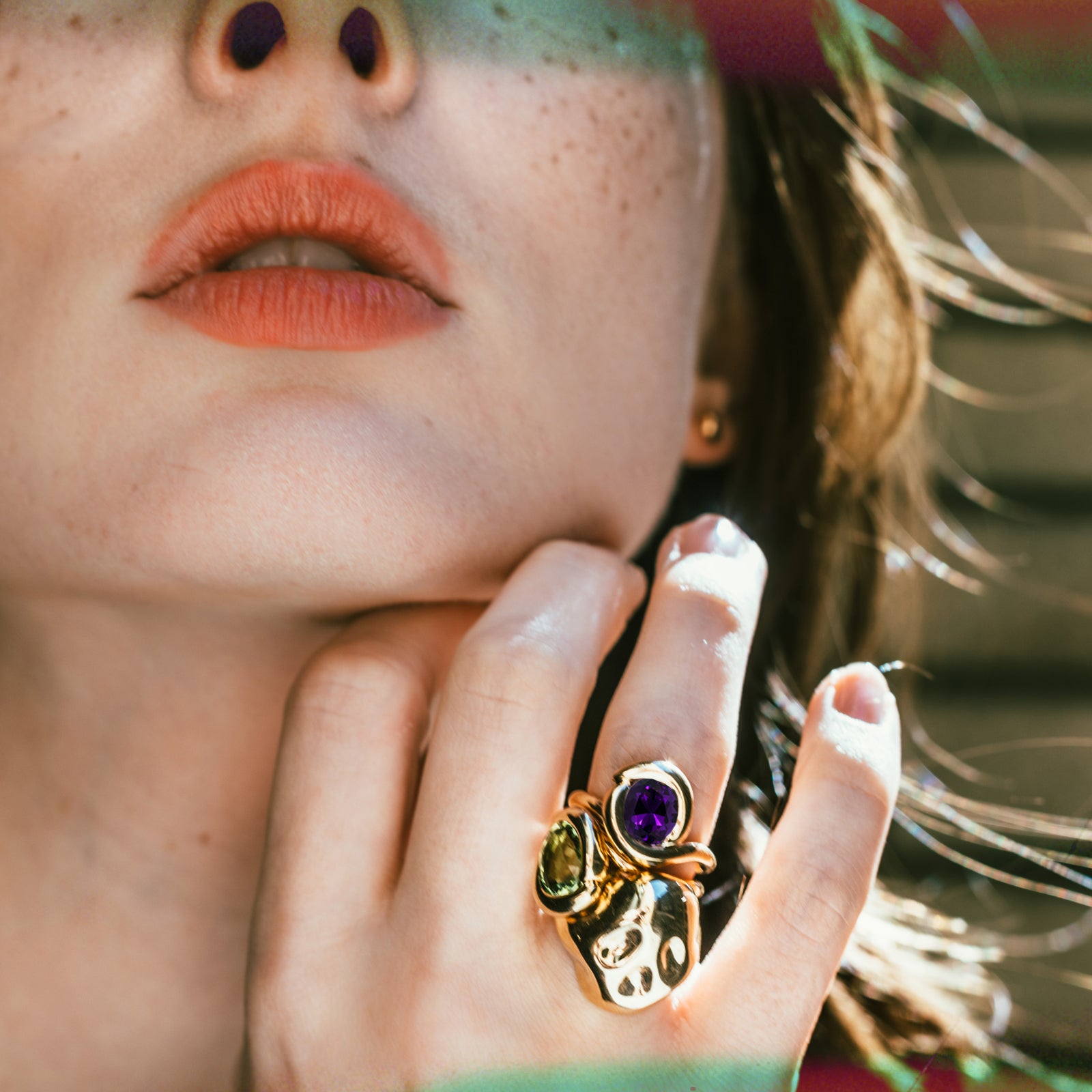 Molten knot ring with deep, rich purple amethyst gemstone layered with a molten knot ring with green tourmaline and a molten skull ring on a model's hand.