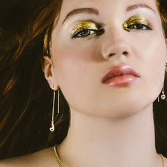 molten drop threader earring with molten droplet threader earring on model with molten gold eye shadow.