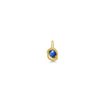molten solitaire knot charm with star sapphire in yellow gold on a white background next to a ruler.