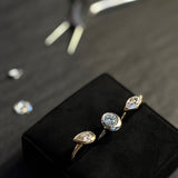 Three molten solitaire rings rest on a jewelry pillow. The round and marquise rings are white gold, and the pear is yellow gold. In the Background rests a pair of jewelry pliers and some loose diamonds. The rings feature 14K recycled gold and ethically sourced lab grown diamonds.