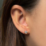 Single molten solitaire stud earring with a round diamond in yellow gold on the ear. 
