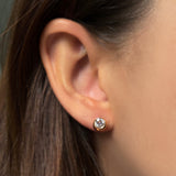 Single molten solitaire stud earring with a round diamond in yellow gold on the ear. 