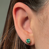 AMANDA PEARL Molten solitaire stud in recycled 14k gold with cultured emerald on a model's ear.