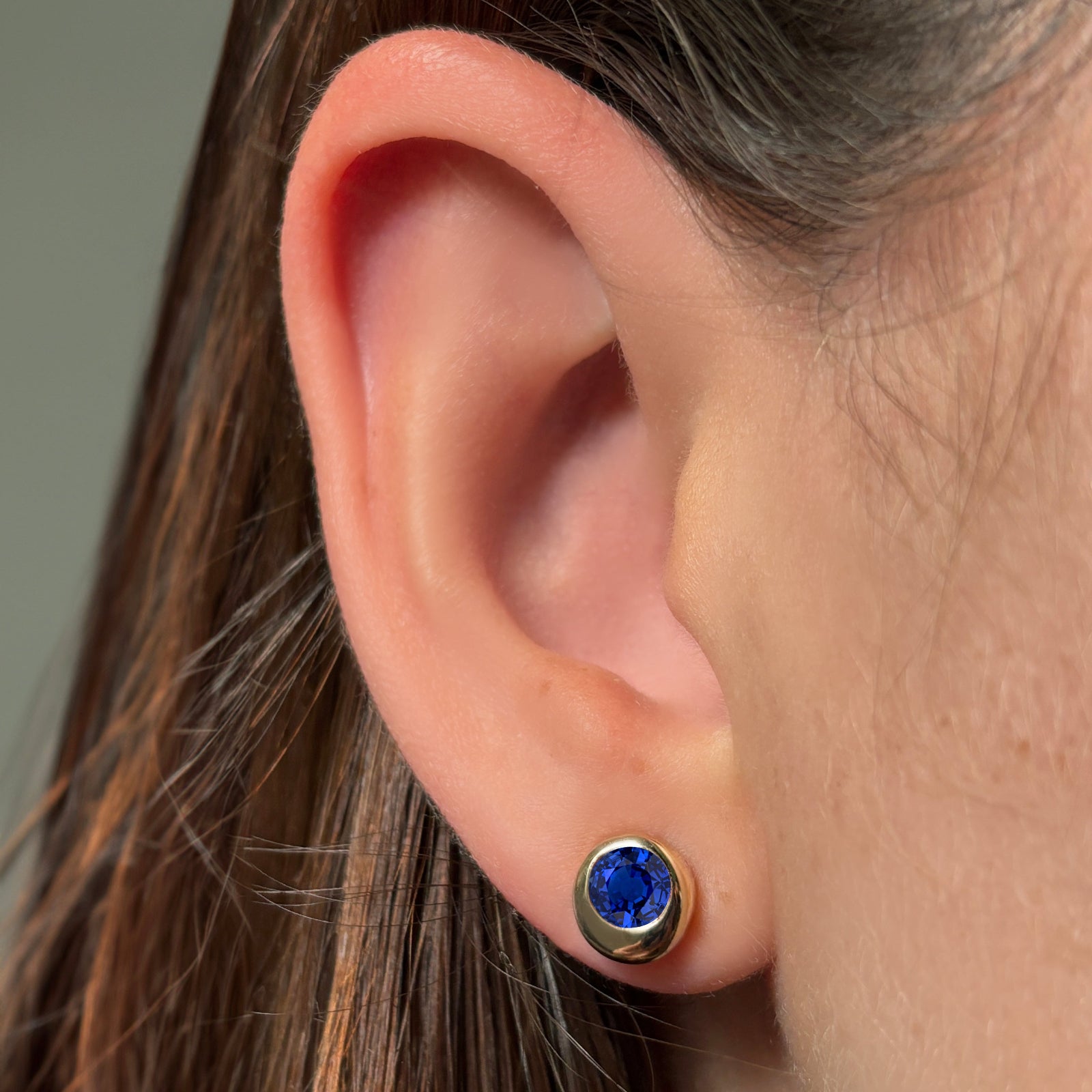 AMANDA PEARL Molten Solitaire stud in recycled 14k gold with a cultivated sapphire on a model's ear.