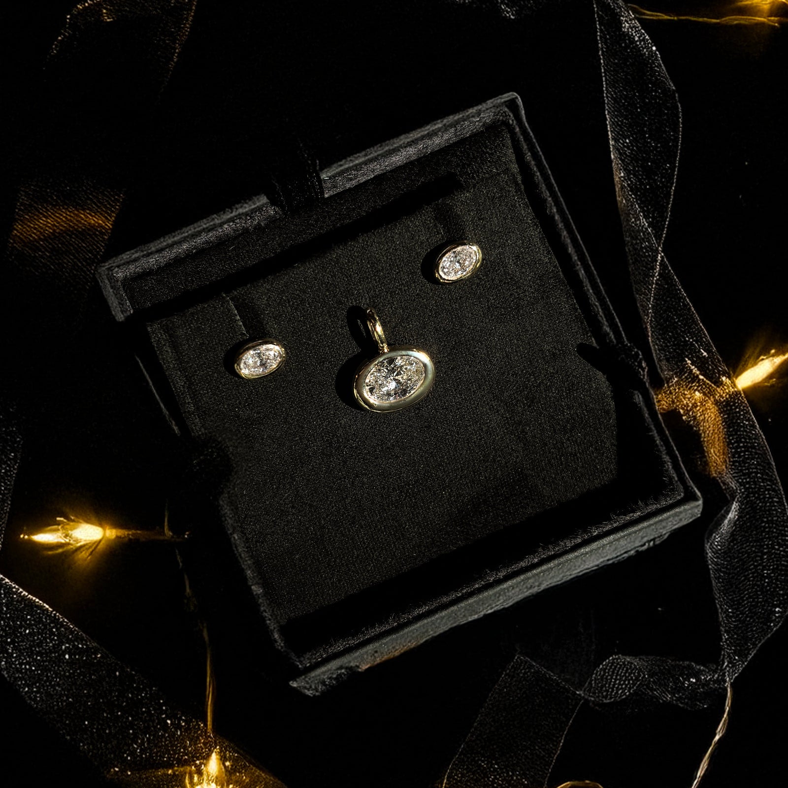 Molten Solitaire studs and charm boxed for a holiday gift with ribbons and holiday lights.