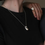 Model wearing an AMANDA PEARL sterling silver bead chain with molten drop charm, with her boyfriend's hand on her shoulder wearing a molten skull ring.