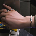 Hand with AMANDA PEARL recycled sterling silver rings and cuff with a metro card going into the nyc subway.